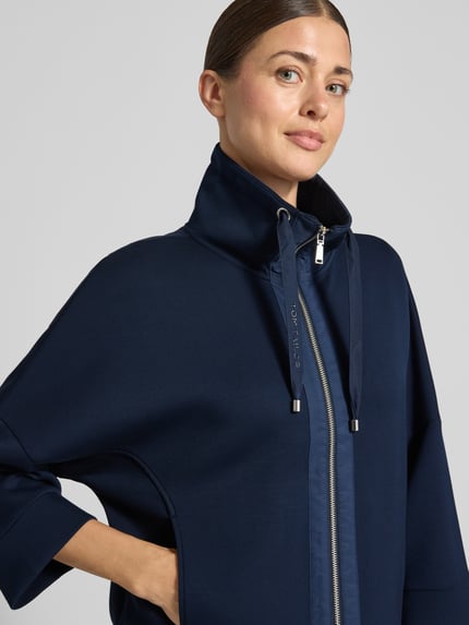 Frauenmodel trägt dunkelblaue Boxy Fit Sweatjacke mit Viskose-Anteil von Tom Tailor, glatte Struktur, Nahaufnahme Oberkörper, Damen Sweatjacke.