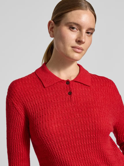 Frauenmodel trägt Regular Fit Strickpullover aus Woll-Mix mit Alpaka-Anteil von Closed in Rot, Zopfmuster, Polo-Kragen, Nahaufnahme Oberkörper.