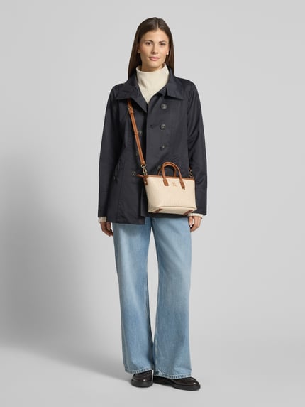 Frauenmodel trägt Henkeltasche mit Logo-Applikation Modell 'MONOPLAY' von Tommy Hilfiger in Beige mit Allover-Muster, Kunstleder, Ganzkörperansicht von vorne
