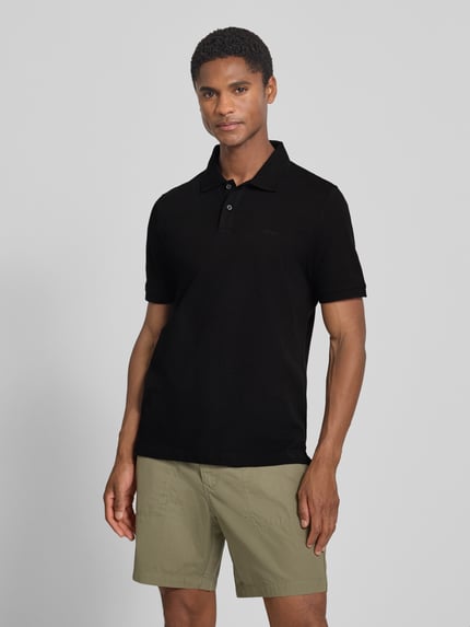 Männermodel trägt schwarzes Regular Fit Poloshirt aus reiner Baumwolle von s.Oliver RED LABEL, glatte Textur, Ganzkörperansicht von vorne.