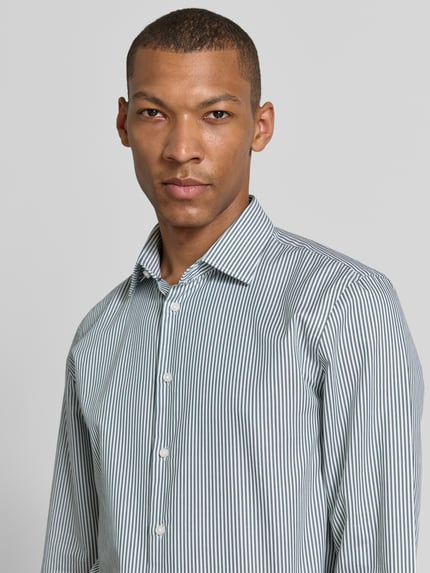 Männermodel trägt Slim Fit Business-Hemd mit Kentkragen von Jake*s aus Reine Baumwolle mit Knopfleiste, Sportmanschetten, Nahaufnahme Oberkörper.