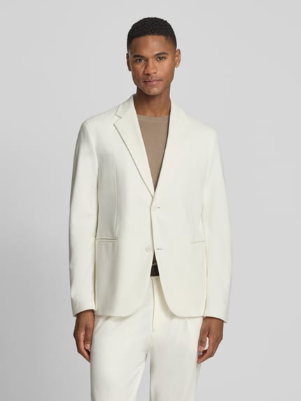 Männermodel trägt Regular Fit Blazer mit Reverskragen Modell 'Catory' von Drykorn, Baumwoll-Mix, cremefarben, Paspeltaschen, 2-Knopfleiste, Ganzkörperansicht von vorne. Rückenlänge bei Größe 50: 70 cm, Schulterbreite 44 cm, Ärmellänge 64 cm.