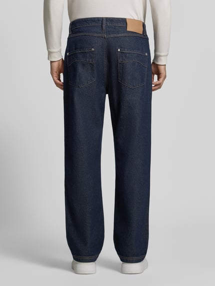 Männermodel trägt dunkelblaue Regular Fit Jeans mit Label-Patch von RETERNITY, Raw Denim, Kontrastnähte, Ganzkörperansicht Rückansicht.