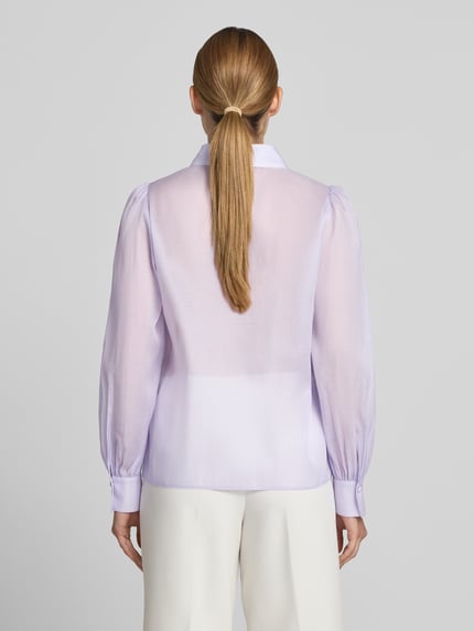 Modelka kobieca ma na sobie Regular Fit Bluse aus Seide-Baumwoll-Mix marki Marc Cain, kolor jasnofioletowy, kołnierzyk koszulowy, listwa guzikowa, długość tyłu w rozmiarze 36: 61 cm, długość rękawów w rozmiarze 36: 64 cm, mieszanka jedwabiu i bawełny, widok całej sylwetki od tyłu.