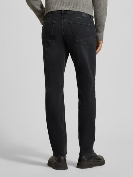 Männermodel trägt Jeans im Used-Look Modell 'Chuck' von Brax aus Baumwoll-Mix mit Stretch-Anteil, Regular Fit, Eingrifftaschen, Ganzkörperansicht Rückansicht.