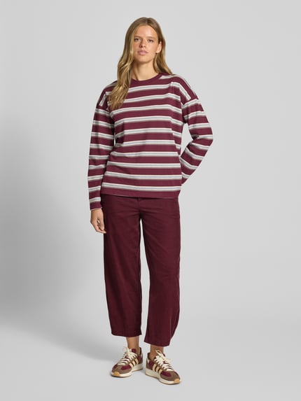 Modelka nosi Loose Fit Cordhose aus reiner Baumwolle von Marc O’Polo DENIM w kolorze bordowym, widok całej sylwetki z przodu.