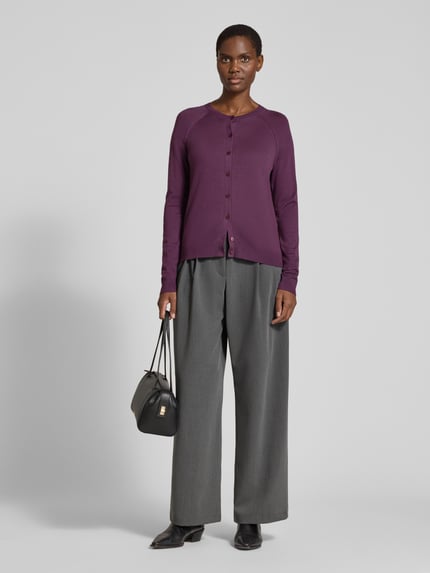 Frauenmodel trägt Strickjacke aus Wolle mit Raglanärmeln von BOSS, unifarbenes Lila, Feinstrick, Rundhals, Knopfleiste, gerippte Abschlüsse, Ganzkörperansicht von vorne.