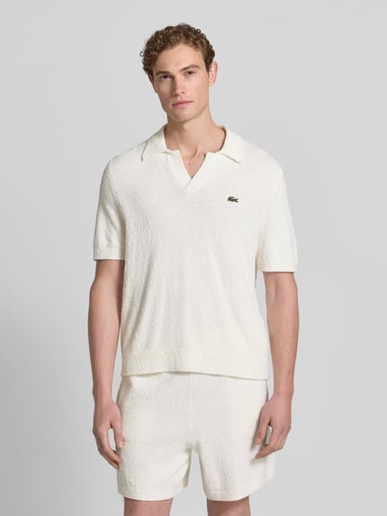 Männermodel trägt Regular Fit Poloshirt aus Baumwoll-Mix von Lacoste, Optik: Unifarben, Bouclé-Textur, Label-Patch, Ganzkörperansicht von vorne.