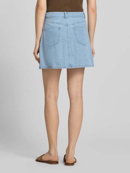Vrouwenmodel draagt A-lijn dames jeansrok van Pieces, model 'ABBI' in denimlook, mix van katoen en viscose, minilengte, twill, 5-pocketmodel, lichtblauw. Ganzkörperansicht Rückansicht.