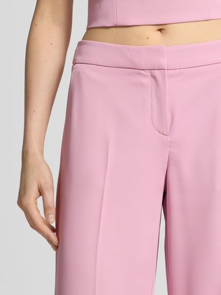 Frauenmodel trägt Hose mit weitem Bein und Paspeltaschen am Gesäß von Jake*s Cocktail in Rosa, Material-Mix mit Stretch-Anteil, Nahaufnahme Oberkörper.