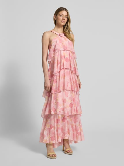 Frauenmodel trägt Volant Abendkleid mit V-Ausschnitt Modell 'FELICIA' von Vero Moda in Rosa mit Blumenmuster aus Chiffon, Ganzkörperansicht von vorne.