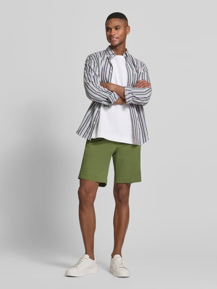 Męski model nosi Straight Fit Chinoshorts aus Baumwoll-Mix von Polo Ralph Lauren, efekt: jednolity kolor, detal z logo, szlufki na pasek, zapięcie na guzik i ukryty zamek błyskawiczny, kieszenie z tyłu i wpuszczane kieszenie boczne, mieszanka bawełny, widok całej sylwetki z przodu.