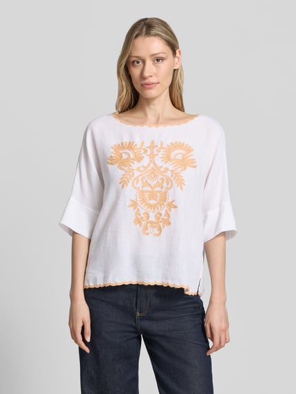 Vrouwenmodel draagt Blusenshirt met Leinen-Anteil und Motiv-Stitching van Christian Berg Woman, witte viscosemix met linnen, loose fit, boothals met contrasterende rand, motiefstitching, ruglengte maat 36: 55 cm, mouwlengte maat 36: 34 cm, voorkant, nahaufnahme bovenlichaam.