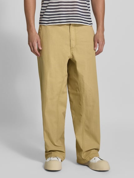 Männermodel trägt Straight Fit Hose aus reiner Baumwolle von Diesel in Beige, sichtbare Gürtelschlaufen und Gesäßtaschen, Nahaufnahme Oberkörper bis Schuhe, reine Baumwolle, Knopf- und Reißverschluss, Bundweite 44 cm, Innenbeinlänge 78 cm.