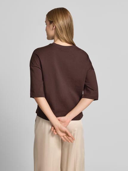 Modelka kobieca ma na sobie T-Shirt mit überschnittenen Schultern Modell 'Sarenzi' od OPUS, bawełna, krój loose fit, kolor brązowy, widok całej sylwetki od tyłu.