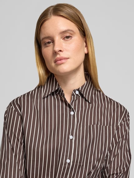 Frauenmodel trägt Regular Fit Bluse aus reiner Baumwolle Modell 'MAVIE' von VILLA SOPHIE mit Allover-Streifenmuster, Nahaufnahme Oberkörper.