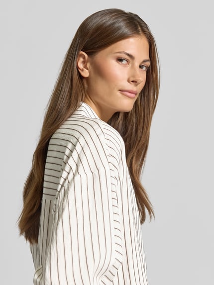 Frauenmodel trägt Loose Fit Langarmbluse aus Viskose Mix Modell 'Foha' von OPUS, cremeweiß mit schwarzen Streifen, Damen Langarmbluse, Ganzkörperansicht Rückansicht.