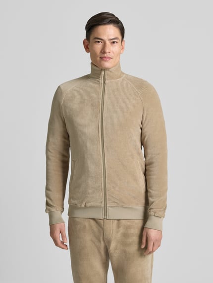 Männermodel trägt Sweatjacke mit Stehkragen von MCNEAL in Beige, Regular Fit, Reißverschluss, gerippte Abschlüsse, Ganzkörperansicht von vorne.