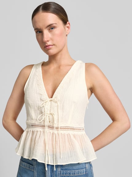Frauenmodel trägt Top aus Lyocell-Mix mit Zierschleifen Modell 'Elena' von Mango in Creme mit taillierter Passform, Nahaufnahme Oberkörper.