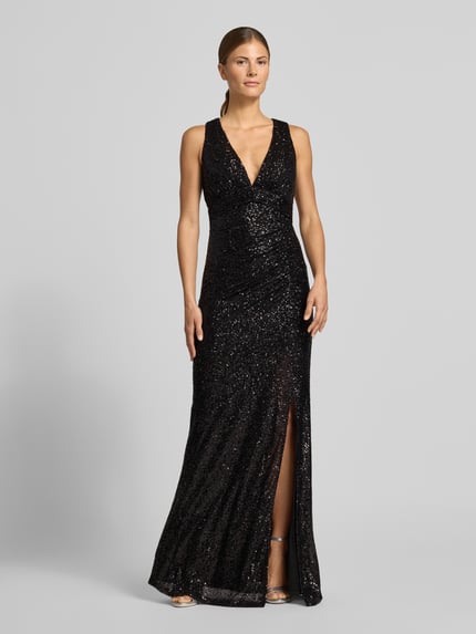 Modelka kobieca ma na sobie sukienkę wieczorową 'Abendkleid mit Pailletten-Cut-Out' od JAKE*S COCKTAIL, błyszczący wzór na całej powierzchni, krój podkreślający figurę, długość maxi, aplikacja z cekinów, marszczenie, rozporek, głęboki dekolt w serek, wszyty zamek błyskawiczny, szerokie ramiączka, bez rękawów, satynowe wykończenie materiału, widok całej sylwetki z przodu.