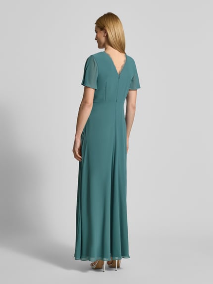 Frauenmodel trägt Damen Abendkleid mit Spitzenbesatz von Christian Berg Cocktail in Türkis, taillierte Passform, semitransparent, Ganzkörperansicht Rückansicht.