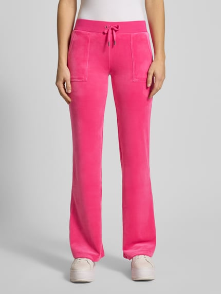 Vrouwenmodel draagt Low Rise Sweatpants met elastische band Model 'LAYLA' van Juicy Couture in felroze katoenmix met stretch, flared cut, steekzakken; dames sweatpants, binnenbeenlengte maat S 39 cm, geheel vooraanzicht.