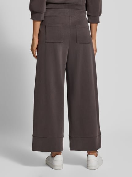Frauenmodel trägt Culotte mit Gesäßtaschen Modell 'Peach' von Rich & Royal in Dunkelbraun, weiter Schnitt, Ganzkörperansicht Rückansicht. Micromodal-Mix mit Stretch-Anteil, elastischer Bund, französische Eingrifftaschen, glatte Textur.