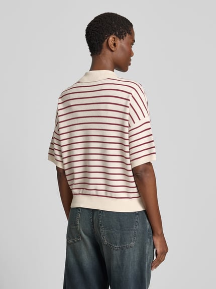Vrouwenmodel draagt Relaxed Poloshirt met wol van ROTATE, wit-rood gestreept, modalmix, relaxed fit, polokraag, tricotlook, met korte mouwen, ruglengte maat S 52 cm. Ganzkörperansicht rückansicht.