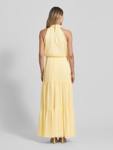 Frauenmodel trägt Abendkleid mit floraler Applikation von Swing aus gelbem Chiffon, Maxikleid, Taillierter Schnitt, Volantsaum, rückseitiger Schlüsselloch-Ausschnitt mit Knöpfen und Reißverschluss, Rückenlänge bei Größe 36: 112 cm, Brustweite 33 cm, Ganzkörperansicht Rückansicht.