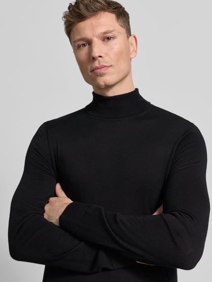Männermodel trägt schwarzen Rollkragenpullover aus reiner Merinowolle Modell 'TRAY' von SELECTED HOMME, körpernaher Schnitt, Nahaufnahme Oberkörper