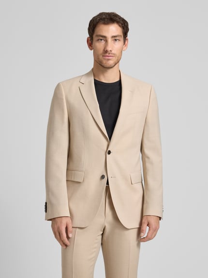 Männermodel trägt Regular Fit Anzugsakko aus schurwoll-mix Modell 'JASPER' van BOSS met all-over motief, licht beige kleur, reverskraag, 2-knoopsluiting, lange mouw met kissing buttons, paspelzak op de borst, klepzakken, rompzoom met dubbele split; regular fit pasvorm. Ganzkörperansicht van voren.