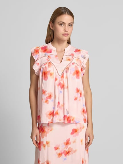 Frauenmodel trägt Blusentop aus Viskose mit V-Ausschnitt Modell 'Mirava' von mbyM, Regular-Fit, Rüschen, florales Muster, Nahaufnahme Oberkörper. Rückenlänge bei Größe S: 61 cm, Ärmellänge: 8 cm.