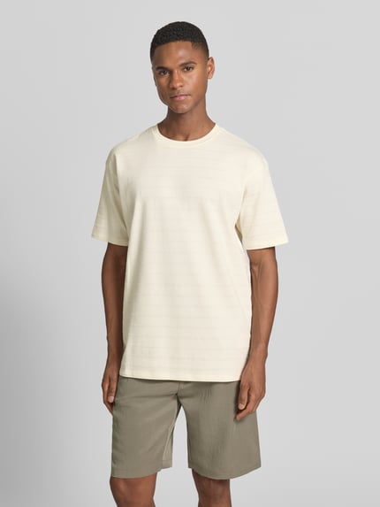 Männermodel trägt T-Shirt mit Strukturmuster und Rundhalsausschnitt von Scotch & Soda, Baumwoll-Elasthan-Mix, Relaxed-Fit, Ganzkörperansicht von vorne.