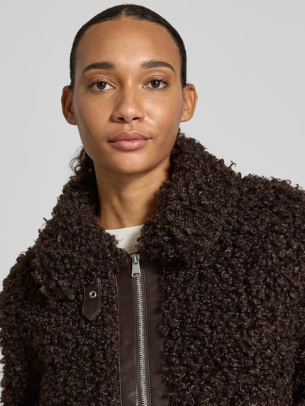 Frauenmodel trägt Teddyjacke mit hohem Stehkragen von ONLY, unifarben, strukturierte Oberfläche, Reißverschluss, Nahaufnahme Oberkörper.