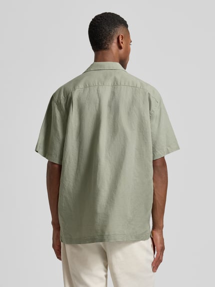 Männermodel trägt Relaxed Fit Freizeithemd aus Leinen-Baumwoll-Mix Modell 'RLXCLAY' von HUGO in Hellgrün, Ganzkörperansicht Rückansicht.