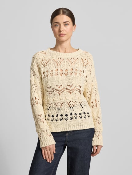 Modelka kobieca ma na sobie Strickpullover mit Rundhalsausschnitt od Oui, bawełniana mieszanka, krój regular fit, kremowy kolor, długość tyłu 54 cm, długość rękawa 43 cm, widok całej sylwetki z przodu.
