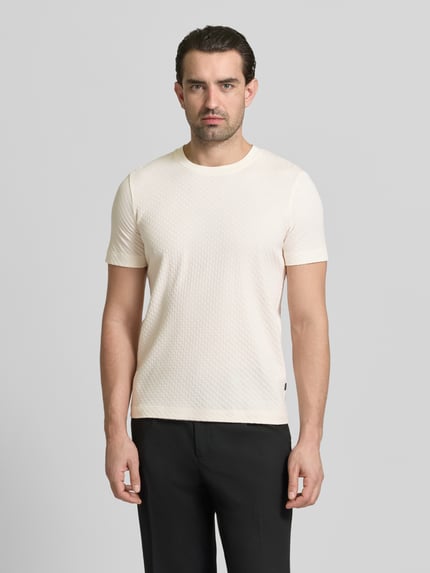 Männermodel trägt T-Shirt mit geripptem Rundhalsausschnitt von JOOP! Collection in Beige, reine Baumwolle, Regular Fit, Ganzkörperansicht von vorne.