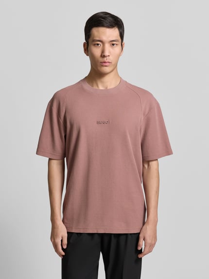 Męski model nosi Regular Fit T-Shirt aus reiner Baumwolle Modell 'DAFFL' von HUGO w kolorze jednolitym, faktura żakardu, krótkie rękawy, okrągły dekolt, aplikacja z logo, widok całej sylwetki z przodu.