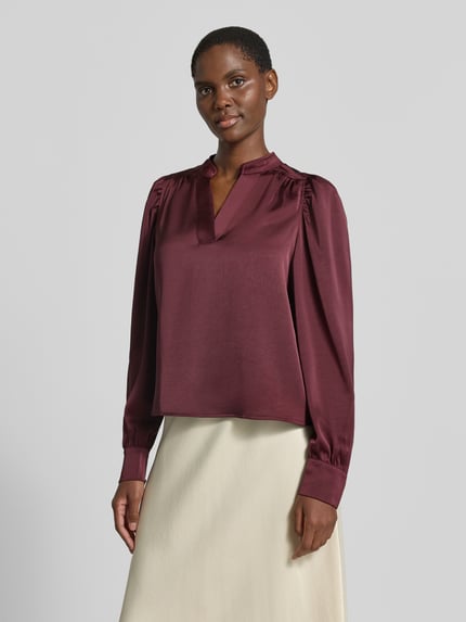 Frauenmodel trägt Langarmbluse mit Stretch-Anteil Modell 'Rosslyn' von Neo Noir in Bordeaux, Satin, lockere Passform, Ganzkörperansicht von vorne.