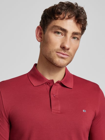 Männermodel trägt Poloshirt mit Label-Stitching Modell 'PAXTON' von Christian Berg Men in Rot, Baumwolle, Nahaufnahme Oberkörper.