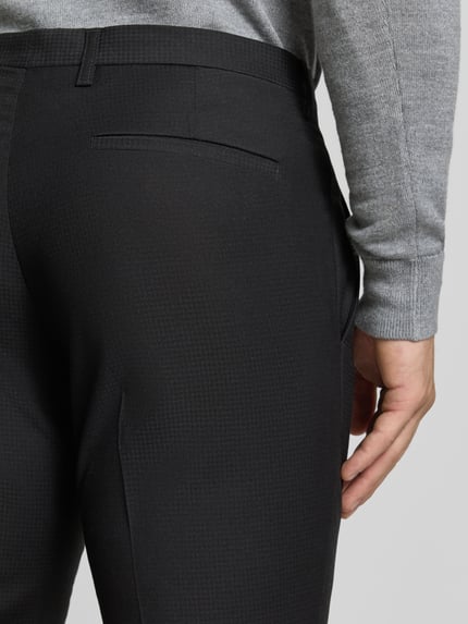 Männermodel trägt Anzughose mit Bügelfalten und Gesäßtaschen von MCNEAL, kleingemustert, schwarze Farbe, Detailaufnahme Rückansicht.