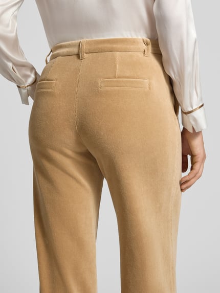 Frauenmodel trägt Wide Leg Anzughose aus Baumwoll-Mix Modell 'WUKARI' von Marc Cain in Beige mit samtiger Textur, Nahaufnahme Rückansicht, Damen Anzughose von Marc Cain.