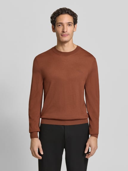 Männermodel trägt Pullover aus Wolle mit Logo-Stitching von BOSS, unifarben, Rundhals, langarm, Feinstrick, Nahaufnahme Oberkörper.