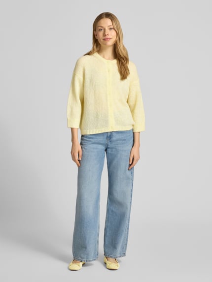 Frauenmodel trägt Cardigan mit Rundhalsausschnitt und Knopfleiste von Luisa Cerano aus Material-Mix mit Alpaka-Anteil in Gelb, Regular-Fit, Rückenlänge 56 cm, Ärmellänge 52 cm, Ganzkörperansicht von vorne.