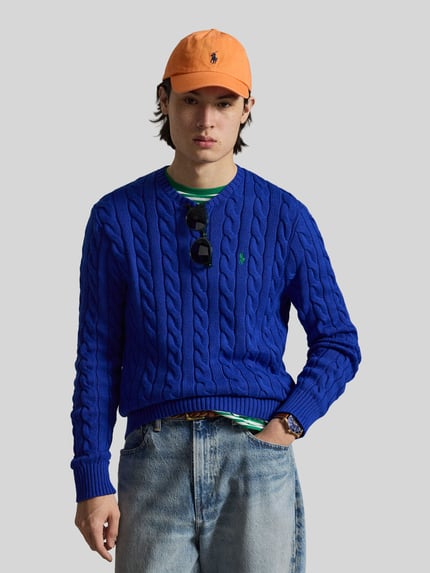 Männermodel trägt Regular Fit Strickpullover aus reiner Baumwolle von Polo Ralph Lauren, Optik: Unifarben, Zopfmuster, Logo-Detail, Strickoptik, Passform: Regular-Fit, Rundhals, Langarm, Materialverarbeitung: Strick, Ganzkörperansicht von vorne.