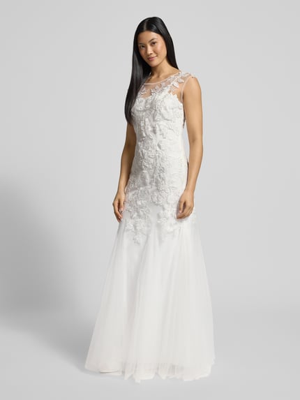 Frauenmodel trägt Brautkleid im Meerjungfrau-Stil von Mascara mit florale Stickereien, Herzausschnitt, breite Träger, Paillettenbesatz, Kurzarm, semitransparentes Obermaterial und blickdichtes Unterkleid, seitlicher Haken- und Nahtreißverschluss, Weiß, Ganzkörperansicht von vorne.