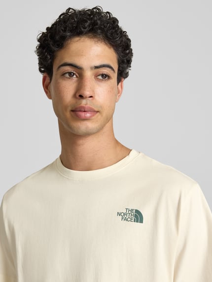 Männermodel trägt Relaxed Fit T-Shirt mit Logo-Print van The North Face in crème, pure katoen, logo op borst, ronde hals, bovenlichaam close-up