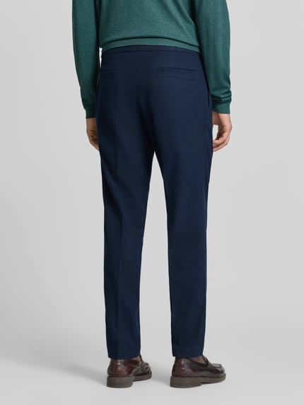 Männermodel trägt Regular Fit Bundfaltenhose mit Seitenriegel von MCNEAL in Dunkelblau mit Gesäßtaschen, Ganzkörperansicht Rückansicht.