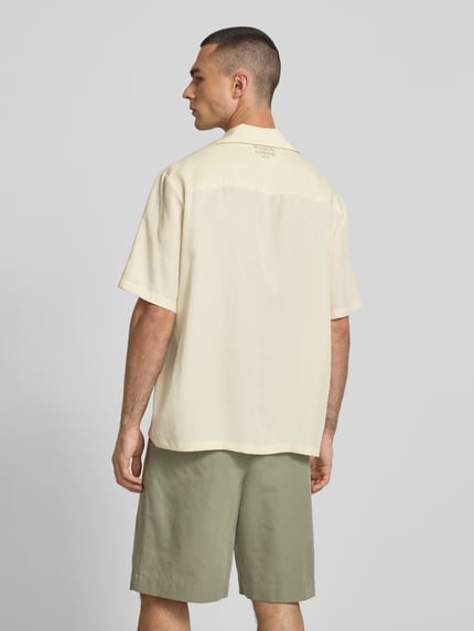 Męski model ma na sobie koszulę casualową 'Freizeithemd aus Lyocell-Mix' od Maison Kitsune, mieszanka lyocellu i lnu, krój relaxed fit, wyhaftowany motyw, kołnierz z połami, z krótkim rękawem, długość tyłu w rozmiarze M: 74 cm, szerokość ramion w rozmiarze M: 49 cm, długość rękawów w rozmiarze M: 30 cm, jasny beż, gładka faktura, całkowita sylwetka z tyłu.