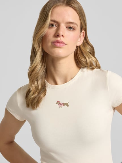 Frauenmodel trägt T-Shirt mit Motiv-Stitching und Rundhalsausschnitt von REVIEW, Baumwoll-Elasthan-Mix, Slim-Fit, Damen T-Shirt, Rückenlänge 54 cm, helle Farbe, feine Struktur, Nahaufnahme Oberkörper.